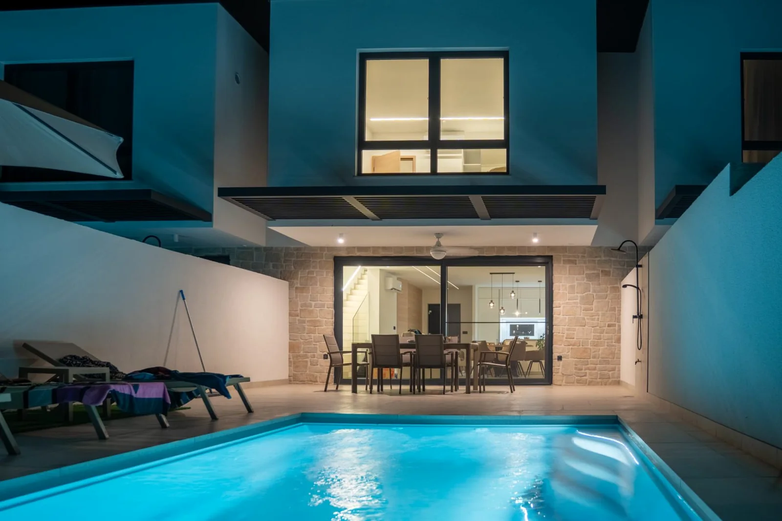 WaterRows Single Series keramisch zwembad met blauwe LED-verlichting in de avond